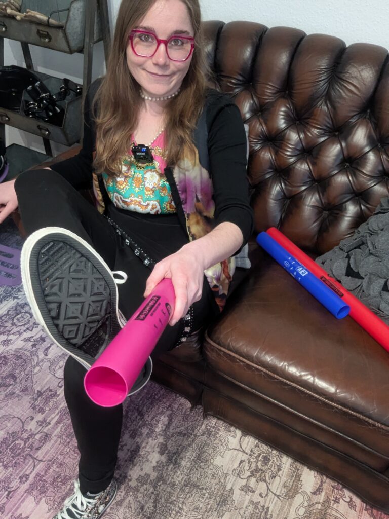 Musikerin spielt pinken Boomwhacker auf ihrem Schuh